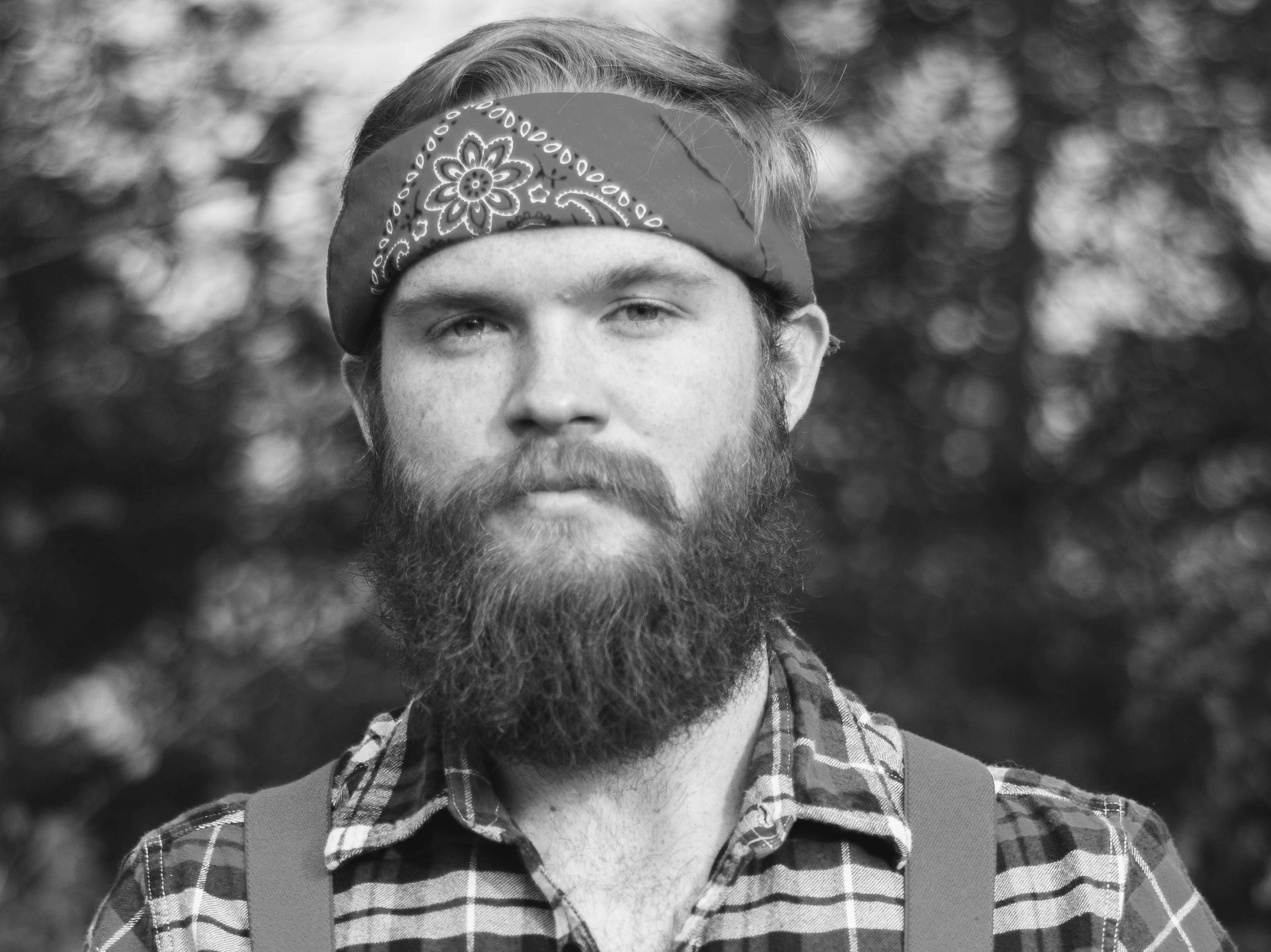 Picture of bearded man outdoors wearing bandana and flannel shirt